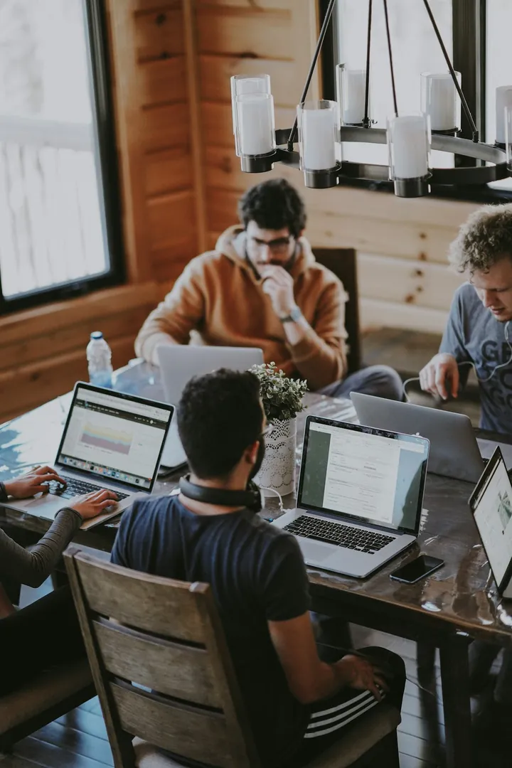 Equipe au travail autour d'une grande table en bois avec laptops