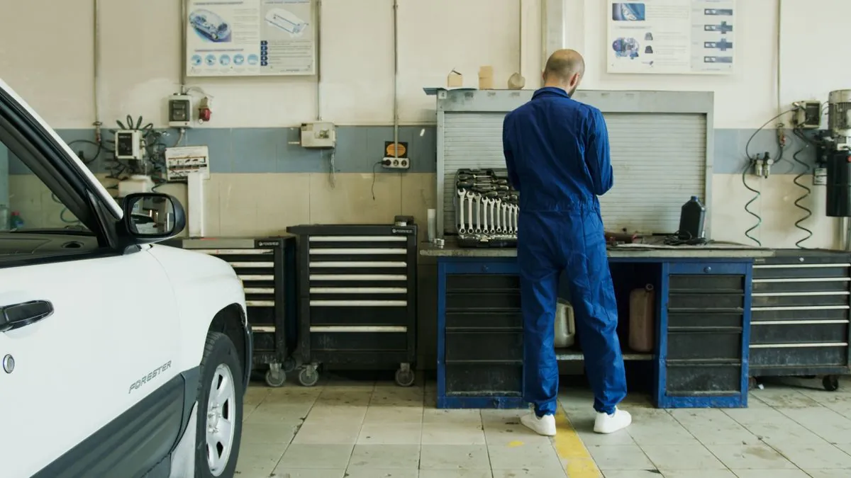 Un mécanicien en combinaison bleue de travail dans un atelier automobile équipé